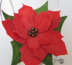 czerwony kwiat z zielonymi liśćmi na białym tle.