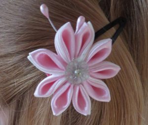zbliżenie na włosy kobiety z różowym kwiatkiem.