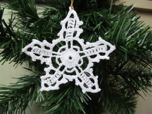 szydełkowana ozdoba w kształcie płatka śniegu zwisająca z choinki.