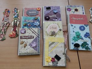 drewniany stół z zeszytami ozdobionymi ręcznie.