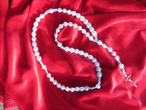 różaniec leży na czerwonym płótnie.