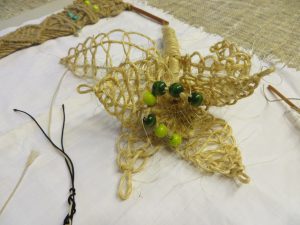 przedmiot w kształcie gwiazdy wykonany ze sznurka i koralików.