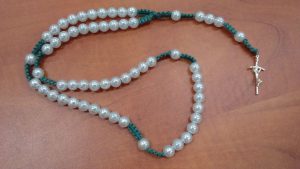 różaniec z krzyżem na drewnianym stole.