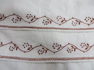 para białego materiału z haftowanymi wzorami.