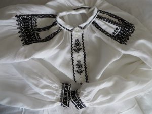 biała koszula z czarnymi lamówkami i kołnierzykiem.