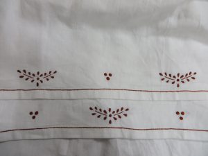 zbliżenie białego materiału z czerwonym haftem.