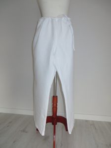 manekin z białą spódnicą na drewnianym stojaku.