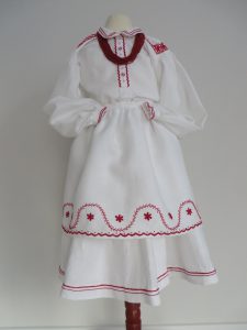 biała sukienka z czerwonym wykończeniem i czerwonym kołnierzykiem.