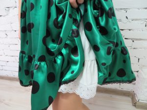 kobieta ubrana w zielono-czarną sukienkę w kropki.