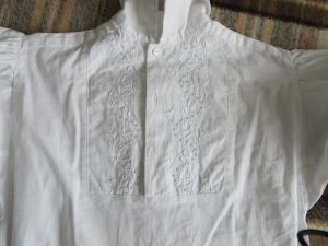biała koszula z haftowanymi detalami.