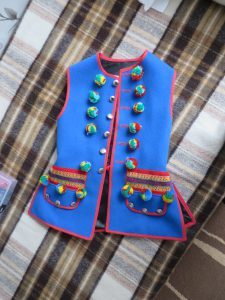 niebieska kamizelka z kolorowymi guzikami.