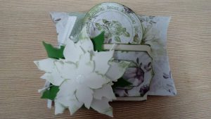 zbliżenie papierowego kwiatka oraz kartki z życzeniami na stole.