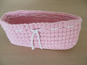różowy koszyczek szydełkowany z białym sznurkiem.