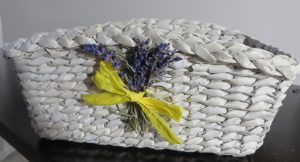 biały kosz z żółtą kokardką i kilkoma kwiatami.