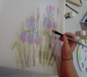 kobieta maluje kwiaty na ścianie.