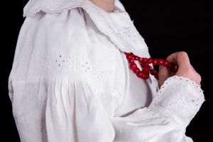 kobieta w białej sukni z czerwonymi koralami.