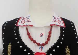 biała koszula z czerwono-niebieskim naszyjnikiem z koralików.