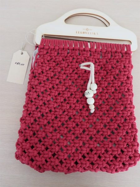 czerwona szydełkowana torebka z białą rączką.